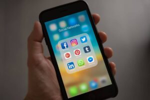 Person Holding a Phone with Social Media Management Icons